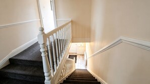 A staircase with white balusters and carpeted steps leading to a landing. - Spacious 4BR House + Garden Retreat | Parking | 7 people (Wallasey)