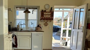 Eine Küche mit Fenster, Spüle, Geschirrspüler und einer Tür, die nach draußen führt.
