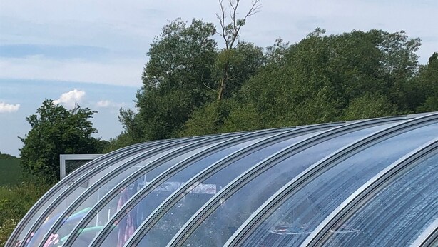 Reihenweise angeordnete, transparente, gebogene Elemente mit rotem Backsteinboden, vermutlich für Sitzgelegenheiten im Freien oder zur Lagerung.