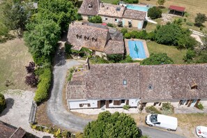 An aerial view of a residential area with stone-roofed houses, a swimming pool, and a white van parked in the driveway. - Holiday Home “Cottage Blanc” with Private Terrace and Wi-Fi (Beaumontois en Périgord)