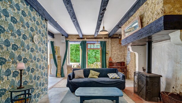 A room with a sofa, a table, a lamp, a fireplace, and a patterned wall.