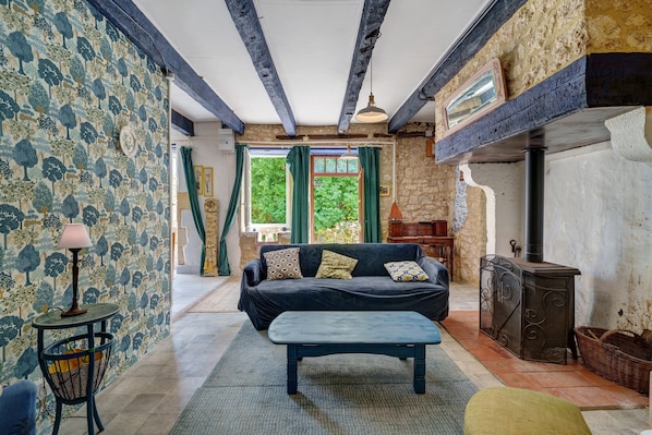 A room with a sofa, a table, a lamp, a fireplace, and a patterned wall.