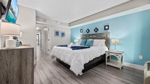 Ein Hotelzimmer mit Bett, Fernseher, Schreibtisch und Stuhl.