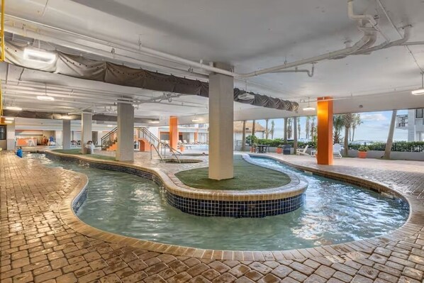 A swimming pool with a tiled edge, surrounded by a brick walkway, and indoor pillars. - Oceanview - Watch Dolphins from balcony - Parking (Myrtle Beach)