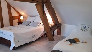 Ein Schlafzimmer mit zwei Betten, Holzbalken und einem Nachttisch mit Lampe.