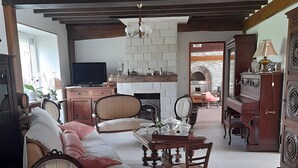 Ein Wohnzimmer mit einer Couch, Sesseln, einem Tisch, einem Fernseher und einem Kamin.