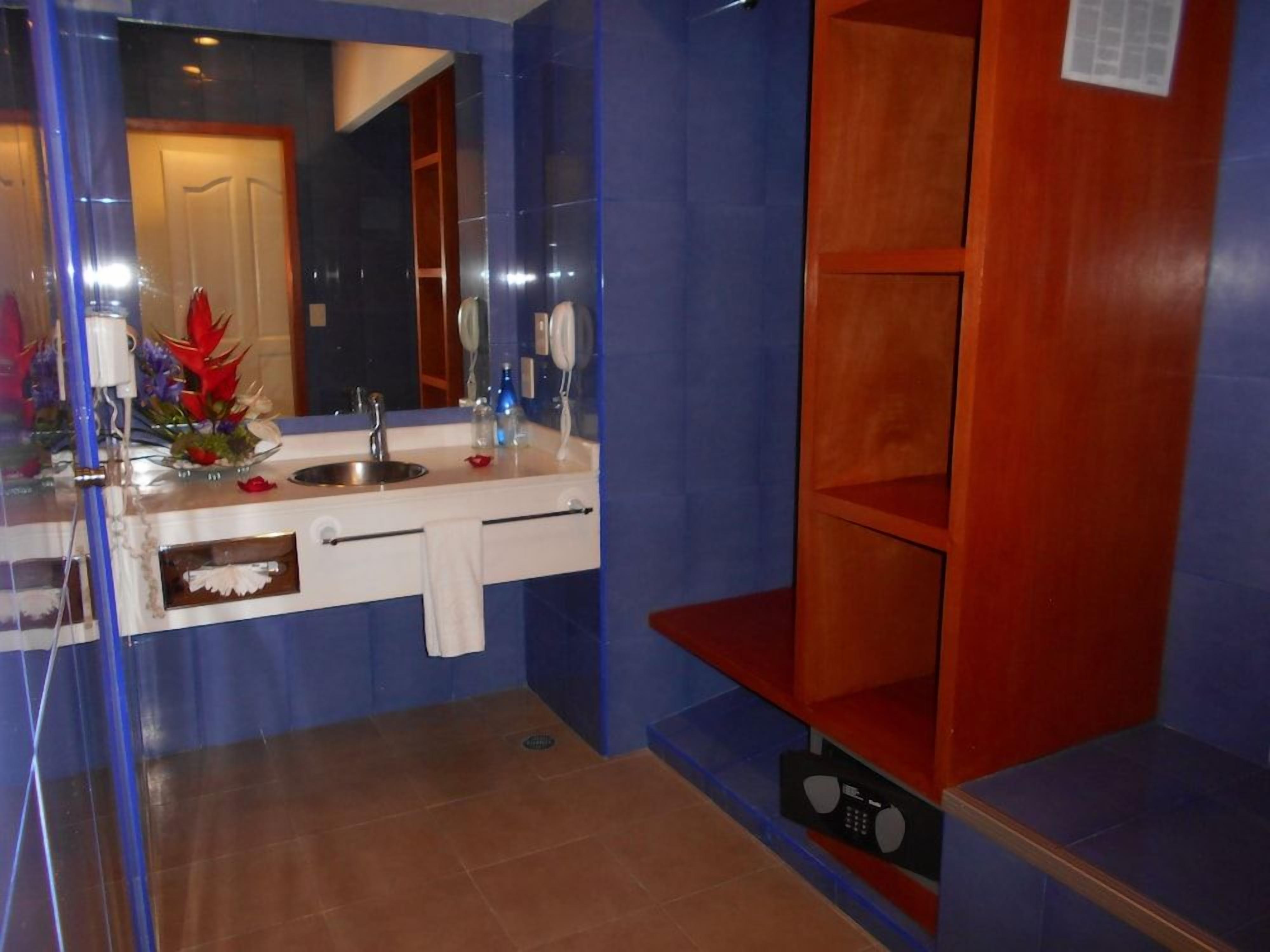 A bathroom with a mirror, sink, and a shelf unit.