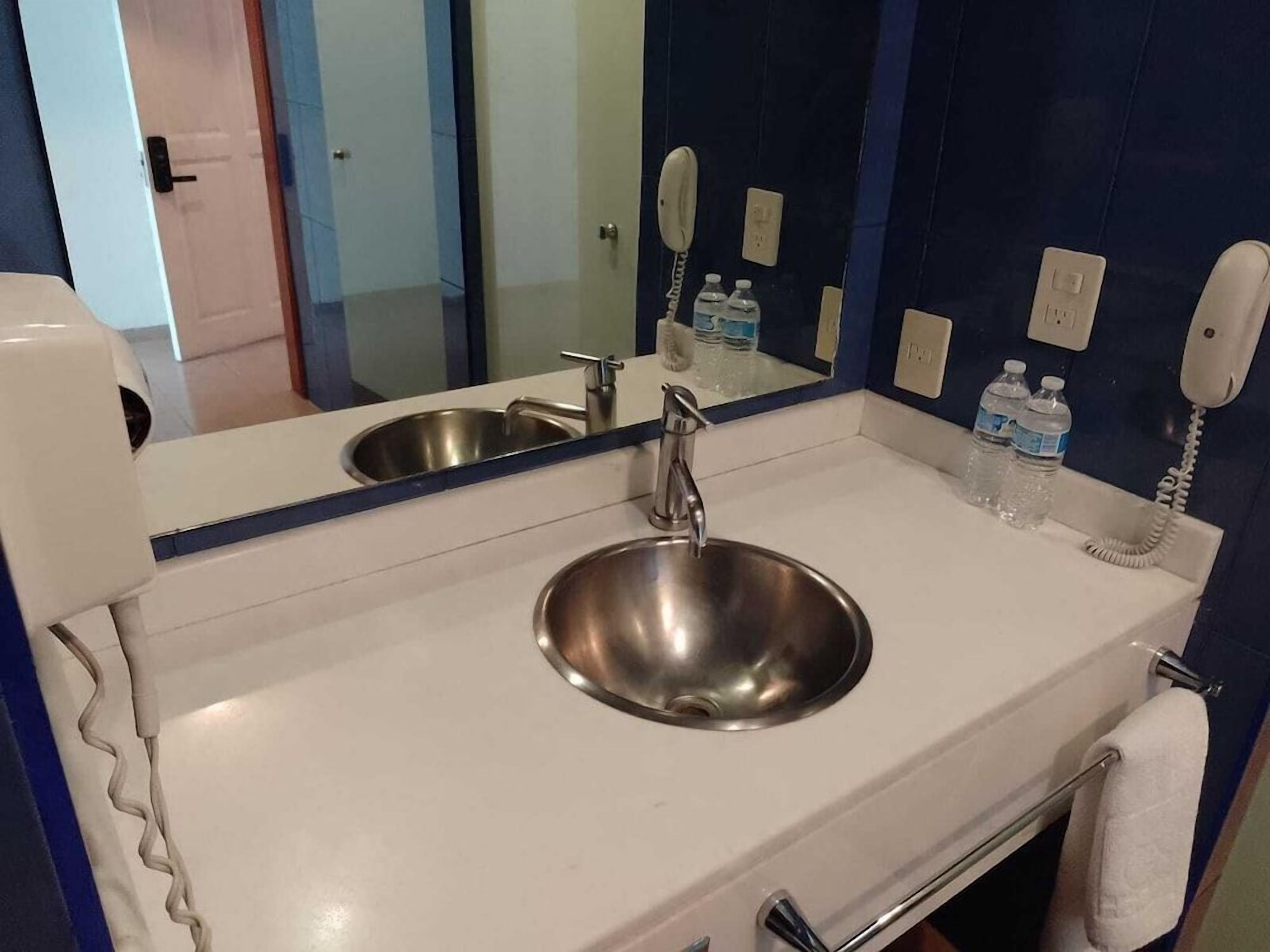 A bathroom with a sink, mirror, and two phones.