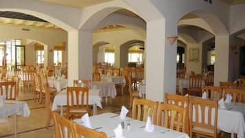 A dining area with tables and chairs, arched ceilings, and natural light.