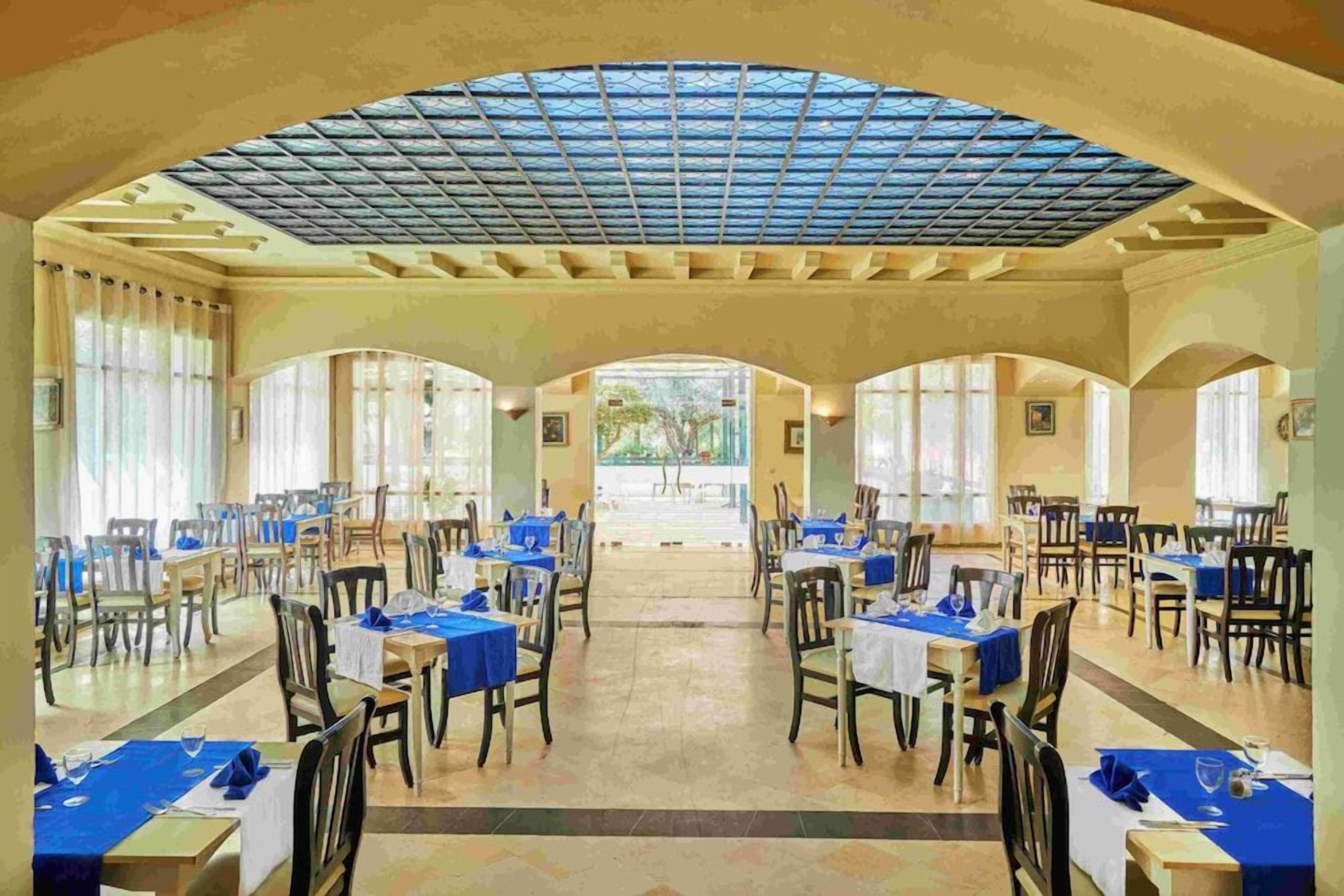 Un vaste espace dédié à la salle à manger, avec des tables disposées pour accueillir de nombreux convives, un grand plafond en arc de cercle et une lumière naturelle provenant des fenêtres.