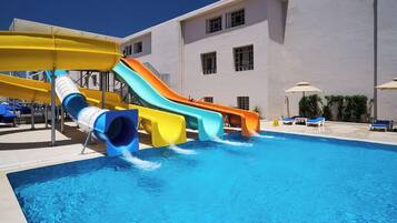 A swimming pool with multiple water slides and lounge chairs.