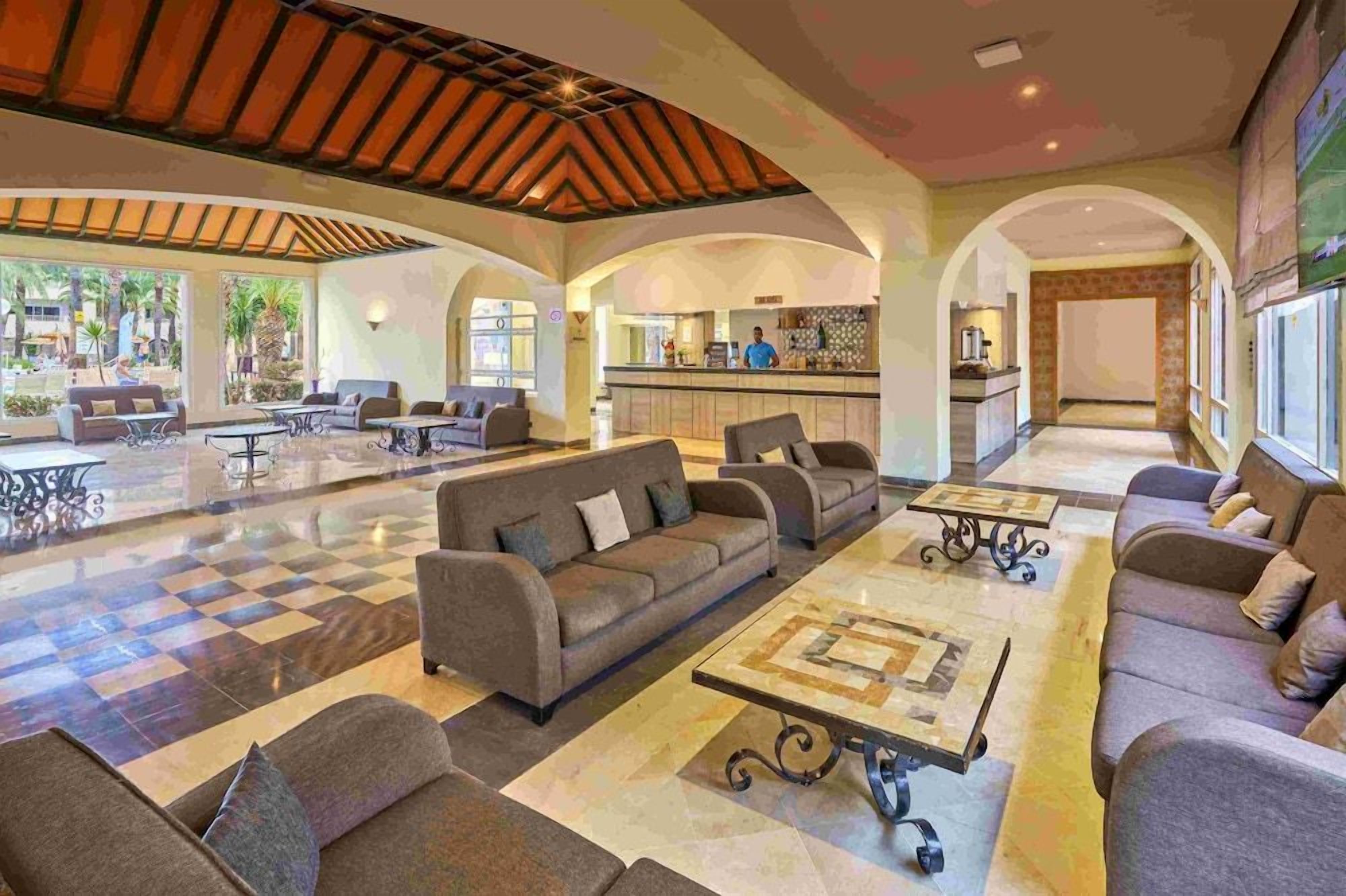 A spacious lobby with a checkered floor, sofas, and a coffee table.