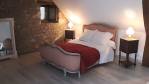 Ein Schlafzimmer mit einem Bett, zwei Nachttischlampen, einem Spiegel und einer Steinwand.