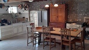 Eine rustikale Küche mit Holzbalken, einer Steinwand und einem Essbereich mit Holztisch und -stühlen.