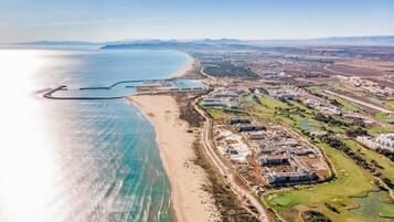 Vue aérienne d’une station balnéaire avec des propriétés situées en bord de mer, des terrains de golf et une marina.