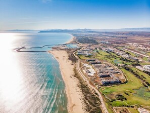 An aerial view of a coastal resort with beachfront properties, golf courses, and a marina. - Oriental Bay Beach Golf and Spa Saida (Saidia)