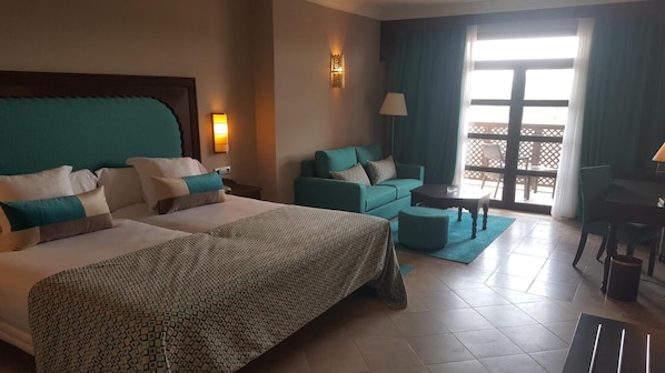 A hotel room with two beds, a sofa, a small table, and a balcony with a view. - Oriental Bay Beach Golf and Spa Saida (Saidia)