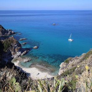 A coastal landscape with clear blue waters, rocky outcrops, and a sandy beach. - Hotel Residence Il Gattopardo (Ricadi)