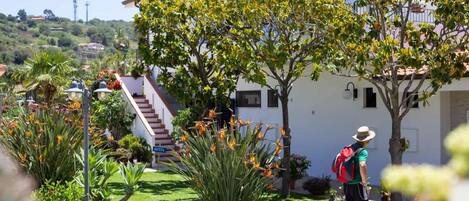 A hotel with a well-maintained garden, a staircase leading to the entrance, and a clear view of the surrounding landscape.