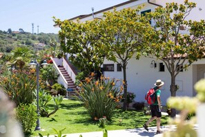 Un hotel con un jardín cuidado, una escalera que lleva a la entrada y una vista despejada del paisaje circundante.