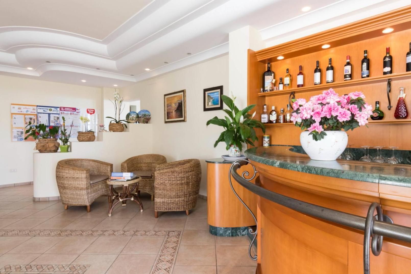 Un'area reception di un hotel con mobili in vimini, un bancone in marmo e una vetrina per il vino.