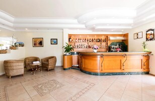 Un hall d’hôtel doté d’un bar, de meubles en osier et d’un sol carrelé.