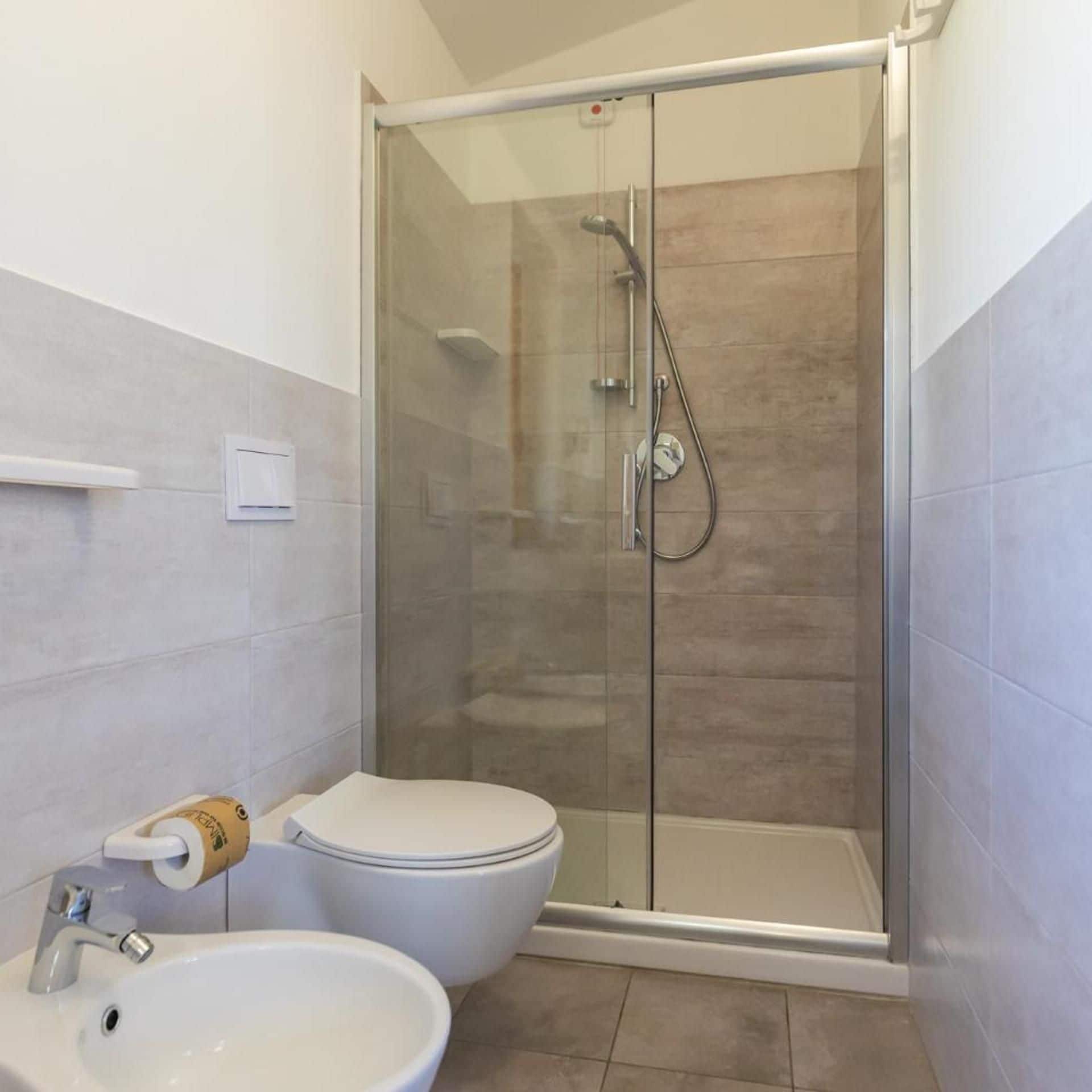 A bathroom with a glass-enclosed shower, a toilet, and a sink.