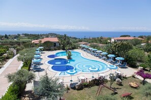 A resort with a large swimming pool, sun loungers, and a view of the ocean. - Hotel Residence Il Gattopardo (Ricadi)