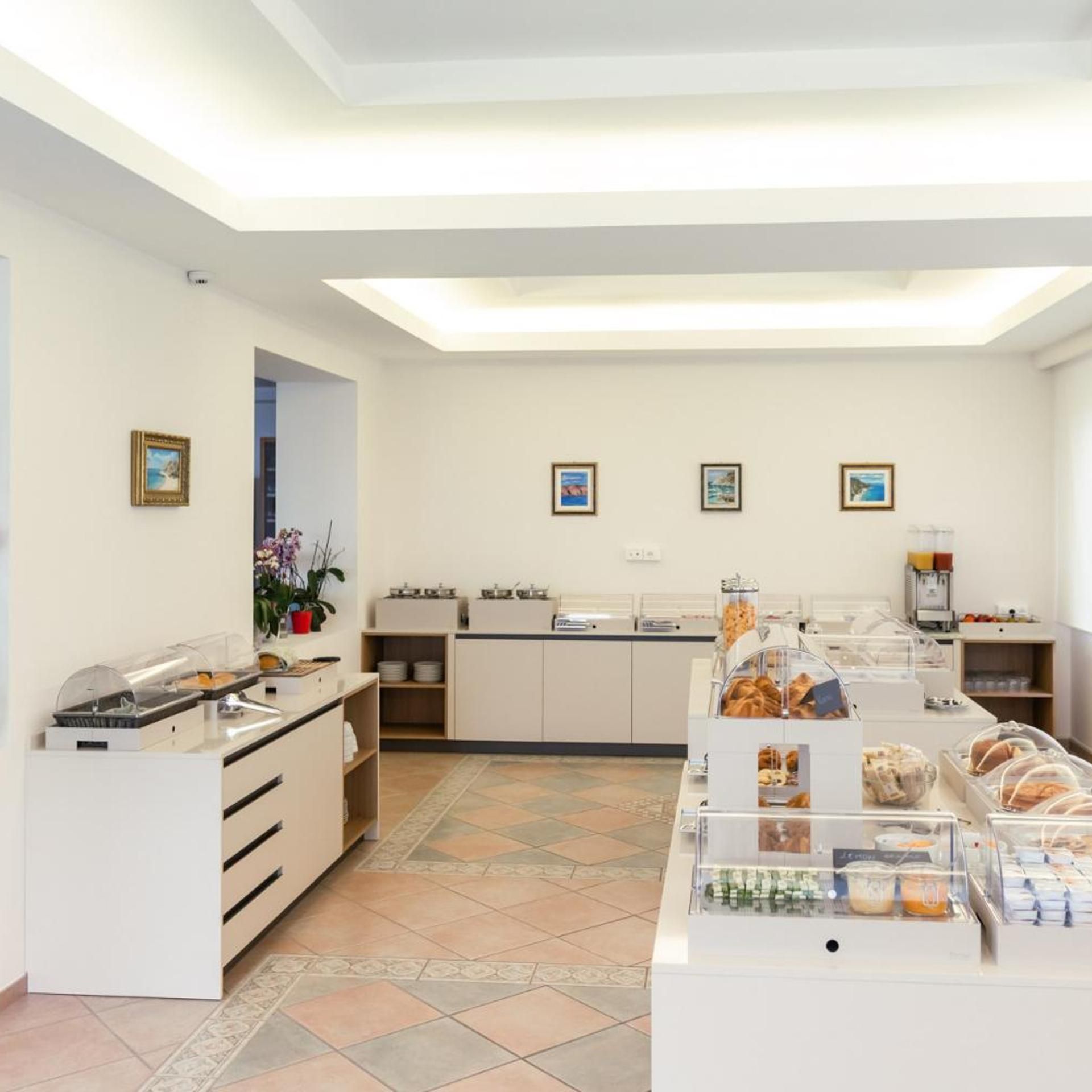 Un'area colazione moderna con un buffet ricco di cibi e una postazione caffè.