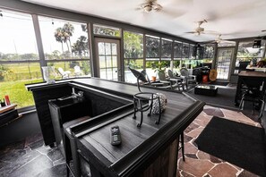 Um quarto espaçoso com grandes janelas, um canto de bar e área externa para sentar.