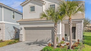 A two-story house with a garage, stone accents, and palm trees in the front yard. - King Ensuite Private Bath Shared Home (Davenport)
