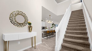 A modern interior with a staircase, a white console table with gold legs, and a decorative mirror. - King Ensuite Private Bath Shared Home (Davenport)