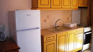 Cuina amb nevera blanca, rentapelats i fogó.