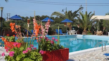 A swimming pool with surrounding plants and umbrellas.