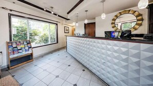 A reception area with a counter, a bulletin board, and a large window. - District Hotel (Portland)