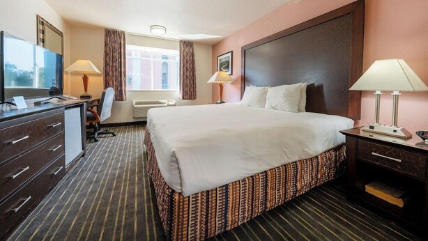A hotel room with a bed, desk, chair, and a television. - District Hotel (Portland)