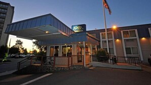 A hotel with a covered entrance, a flagpole, and a signboard. - District Hotel (Portland)