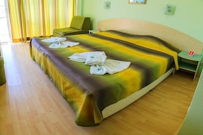 A hotel room with a bed, a chair, a nightstand, and a wall-mounted phone. - Hotel Dalis (Nessebar)