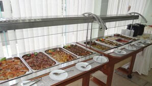 Een buffetopstelling met meerdere food stations, een metalen bedieningsbar en een glazen scheidingswand.