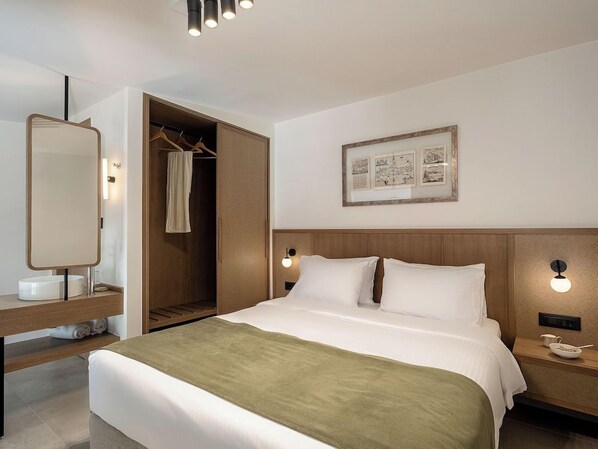 Habitación de hotel con cama, mesitas de noche, un espejo, armario y un cuadro en la pared.