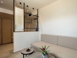 A modern interior with a sofa, a round table with a vase, and a wardrobe. - Inea Hotel and Suites (Chania)