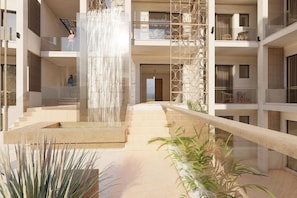 A modern building with a central water feature, multiple balconies, and a staircase leading to the upper levels. - Inea Hotel and Suites (Chania)