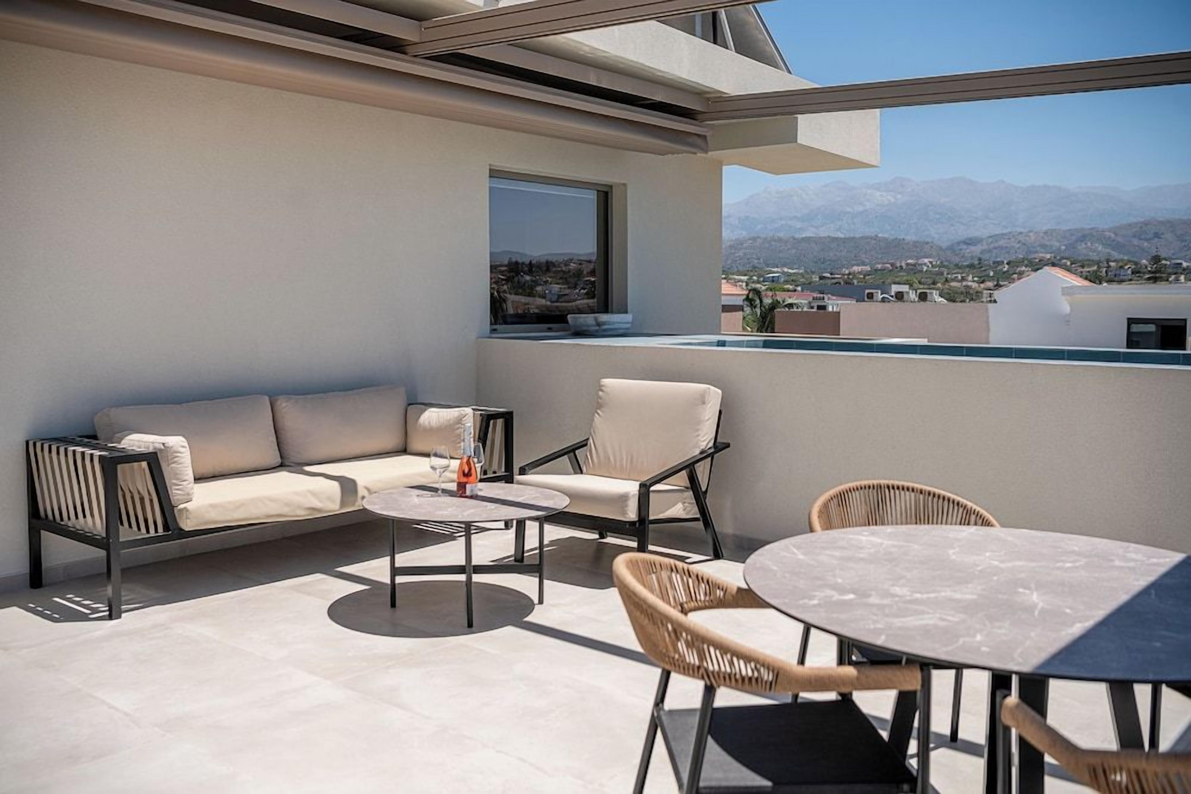 Eine Dachterrasse mit einer Couch, Stühlen, einem Tisch und Blick auf Berge.