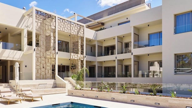 Un edificio moderno de varios pisos con piscina, balcones y zona de estar al aire libre.