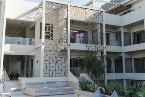 Un edificio de varios niveles con fachada geométrica, asientos exteriores y una escalera que conduce a la entrada.