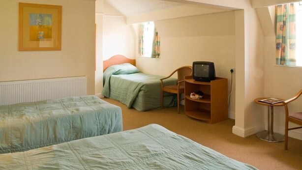 Un dormitorio con dos camas, una silla, un televisor y una mesita.
