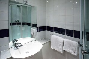 A modern bathroom with a glass-enclosed shower, a white sink with chrome fixtures, and a mirror. - Grand Metropole Hotel Blackpool (Blackpool)