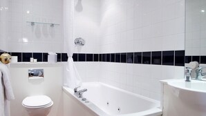 Un baño moderno con inodoro blanco, bañera y lavabo.