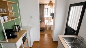 A compact kitchen with a wooden countertop, a sink, and a coffee machine.