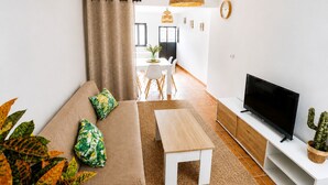 A living room with a sofa, TV, and plants.